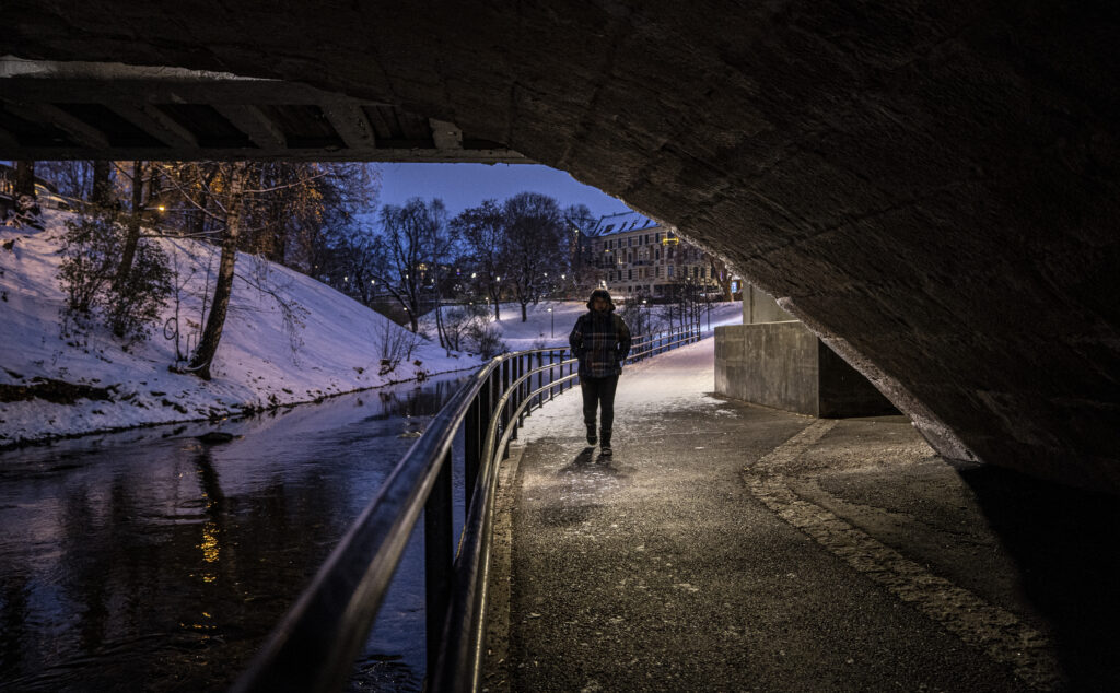 Person som g&aring;r under en bro en m&oslash;rk vinternatt