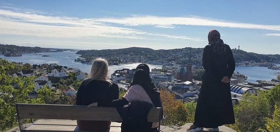 Tre kvinner som st&aring;r p&aring; et utsiktspunkt og ser utover
